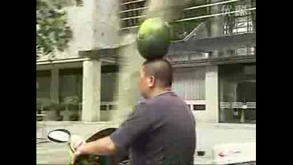 Мъж кара скутер и балансира диня на главата си