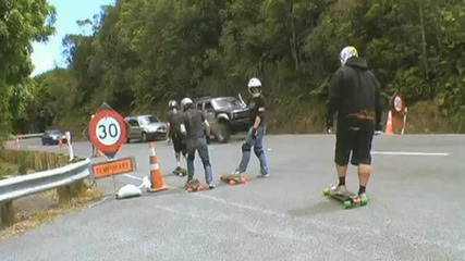 Skateboarders overtake lorry going down hill 