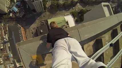Момче изпълнява стойка на ръце на покрива на 40 етажна сграда .