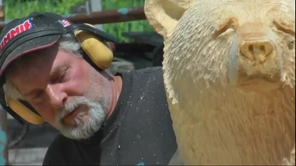 Човек прави мечка от дърво с моторна резачка