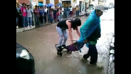 Човек превозва хора от наводнена улица с количка