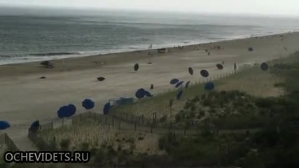 Внезапен вятър на плажа вдига чадърите на туристите във въздуха