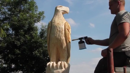 Човек прави орел от дърво с моторна резачка