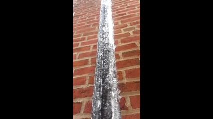 Лед се топи върху замръзналите водосточни тръби