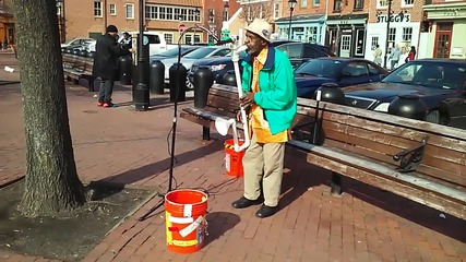Уличен музикант със саксофон, направен от пластмасови тръби
