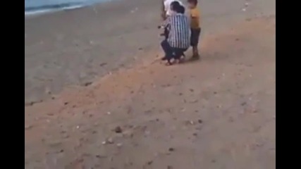 На плажа в Либия, баща учи едно дете да стреля с гранатомет