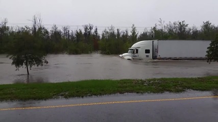 Шофьор на камион кара по наводнена улица