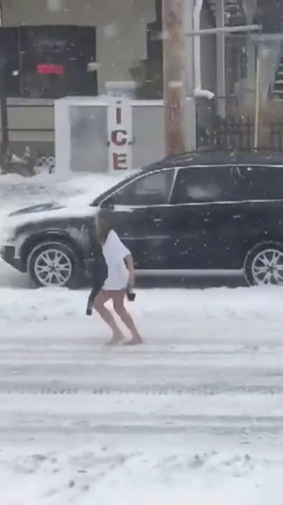 Какво ли е накарало полуголо маце да прибягва по заснежена улица ?